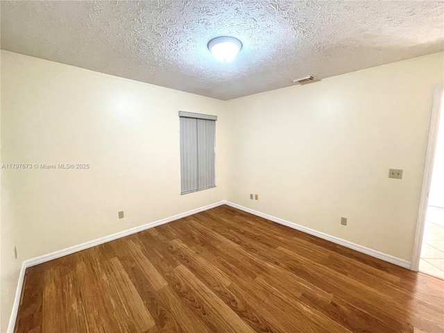 5400 NW Emblem St, Port St Lucie, FL 34983 - empty room featuring dark wood-style flooring, a textured ceiling, and baseboards