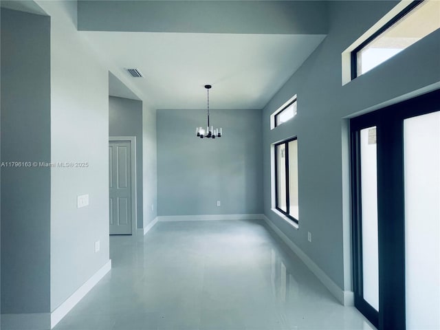 unfurnished room with baseboards, concrete floors, a chandelier, and visible vents