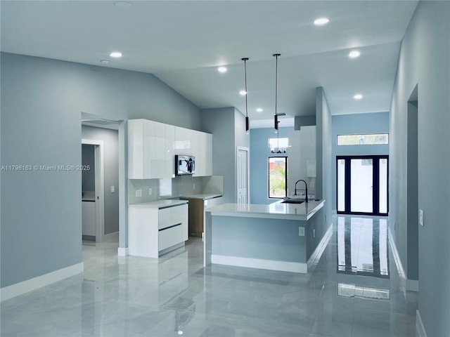 kitchen featuring a sink, white cabinets, baseboards, stainless steel microwave, and modern cabinets
