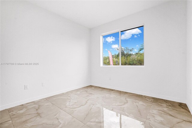 spare room featuring marble finish floor and baseboards
