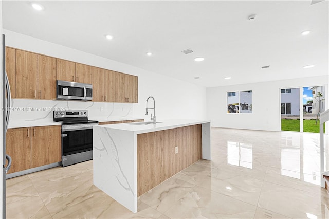 kitchen with a sink, stainless steel appliances, marble finish floor, and a center island with sink