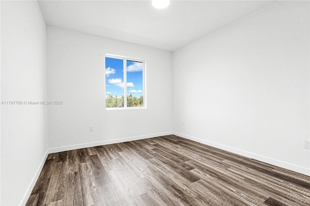 spare room featuring baseboards and dark wood finished floors