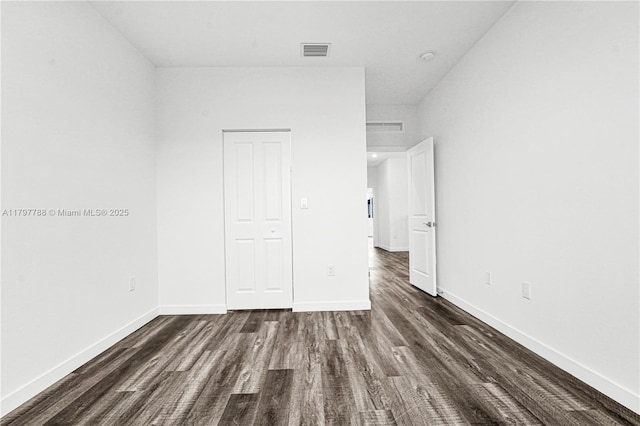 unfurnished bedroom with baseboards, dark wood finished floors, and visible vents