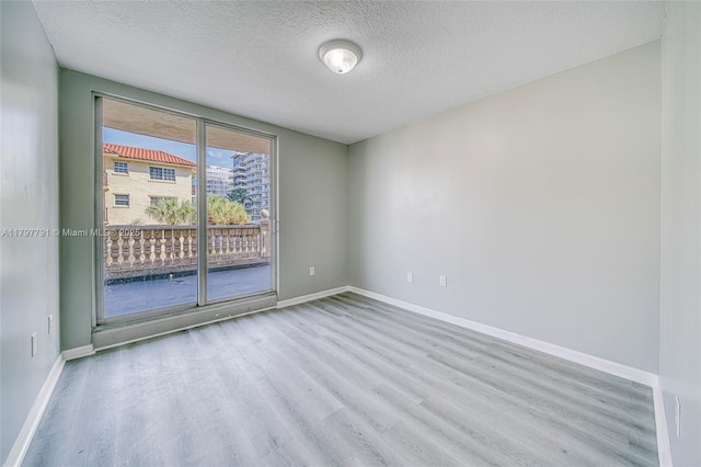 8888 Collins Ave Unit 201, Surfside, FL 33154 - spare room with wood finished floors, a textured ceiling, and baseboards