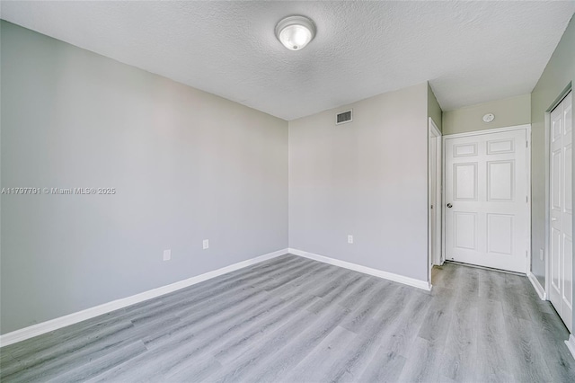 8888 Collins Ave Unit 201, Surfside, FL 33154 - empty room with light wood-style flooring, a textured ceiling, and baseboards