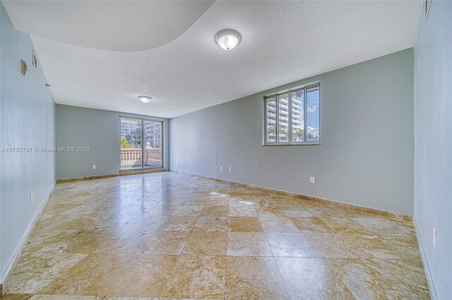 8888 Collins Ave Unit 201, Surfside, FL 33154 - spare room featuring a textured ceiling, baseboards, and stone finish floors