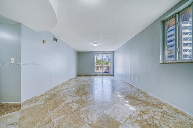 8888 Collins Ave Unit 201, Surfside, FL 33154 - unfurnished room featuring stone tile floors, baseboards, and a textured ceiling