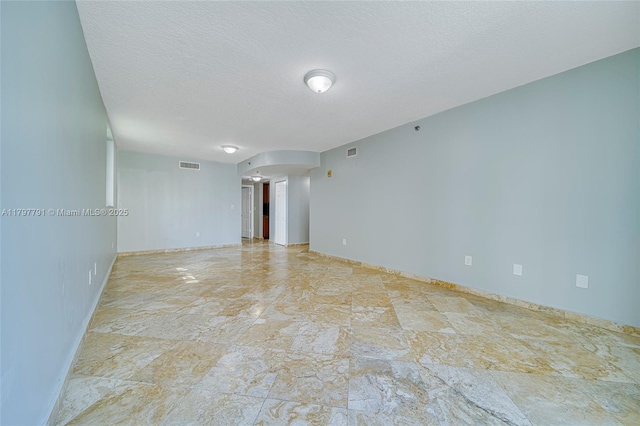 8888 Collins Ave Unit 201, Surfside, FL 33154 - empty room featuring baseboards, a textured ceiling, and arched walkways