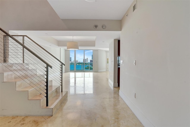 staircase featuring baseboards, a raised ceiling, and visible vents
