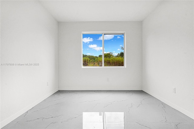empty room featuring marble finish floor and baseboards