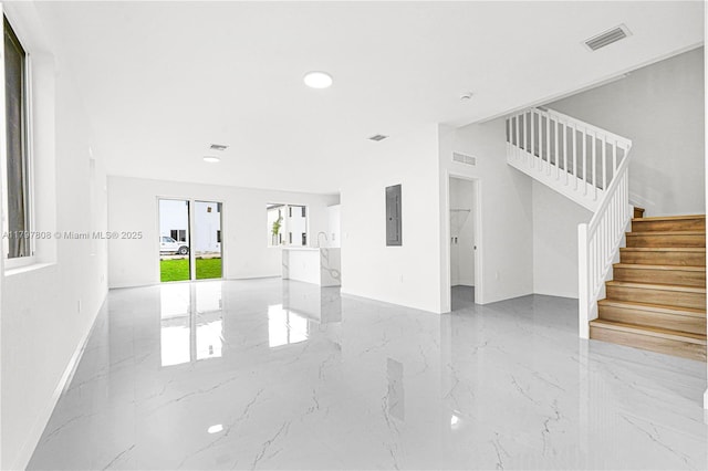unfurnished living room featuring electric panel, stairway, marble finish floor, and visible vents