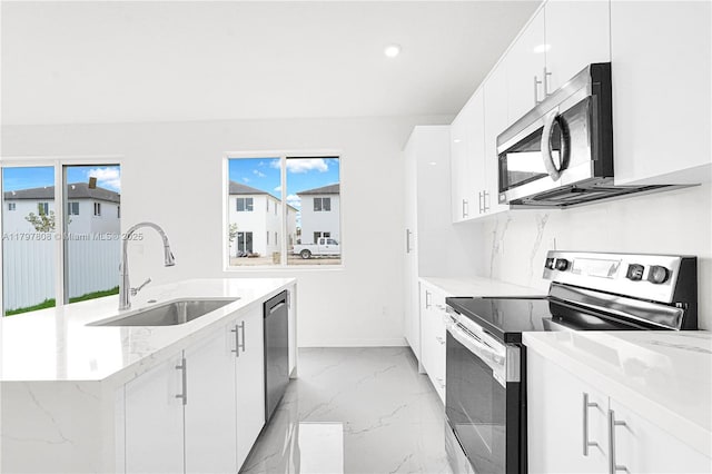 kitchen featuring marble finish floor, a sink, white cabinetry, stainless steel appliances, and a kitchen island with sink