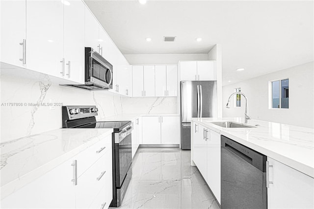 kitchen featuring marble finish floor, light stone counters, stainless steel appliances, and a sink