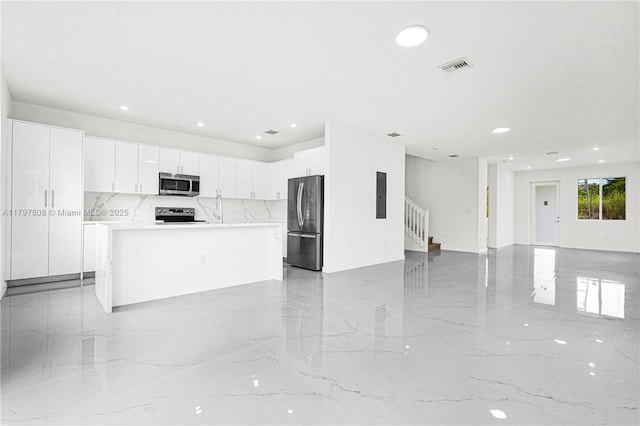 kitchen with stainless steel appliances, white cabinetry, open floor plan, and marble finish floor