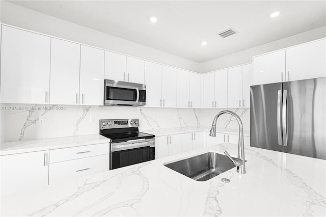 kitchen featuring a sink, visible vents, light stone countertops, appliances with stainless steel finishes, and recessed lighting