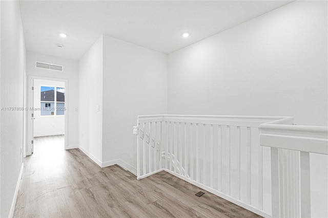corridor with an upstairs landing, wood finished floors, visible vents, baseboards, and recessed lighting