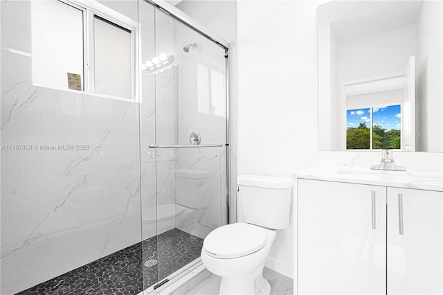 full bath featuring vanity, toilet, a marble finish shower, and baseboards