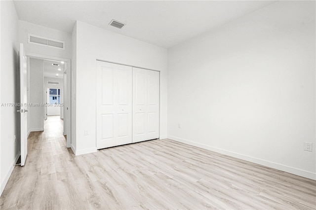 unfurnished bedroom featuring baseboards, visible vents, and light wood-style floors