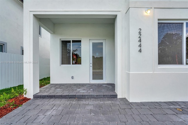 property entrance featuring fence and stucco siding