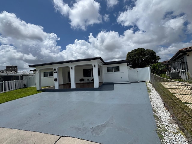 view of front of home with stucco siding, driveway, fence, and a porch