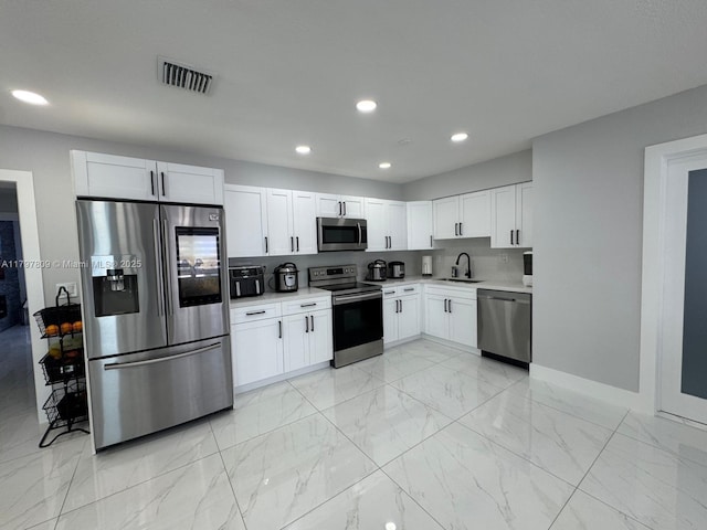 kitchen with marble finish floor, light countertops, appliances with stainless steel finishes, and a sink