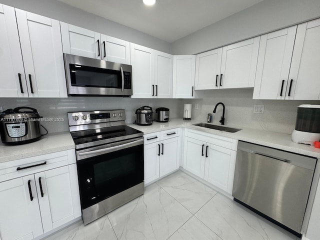 kitchen with a sink, light countertops, marble finish floor, and appliances with stainless steel finishes