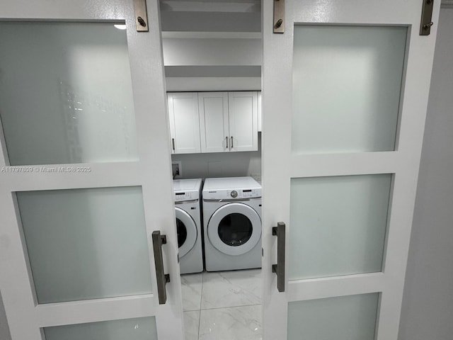 laundry room featuring cabinet space, washing machine and clothes dryer, and marble finish floor