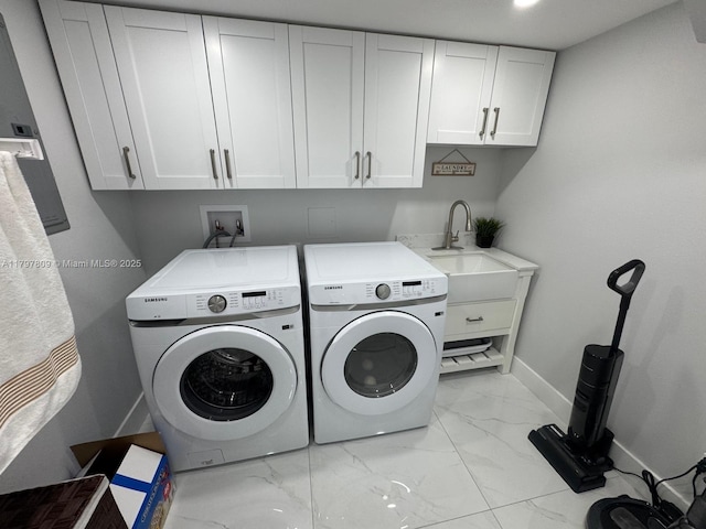 washroom featuring a sink, cabinet space, marble finish floor, washing machine and dryer, and baseboards