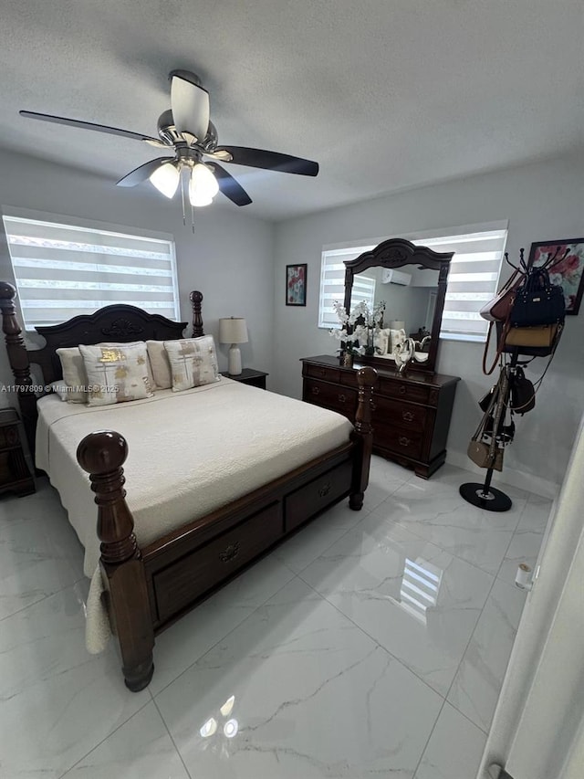 bedroom featuring a ceiling fan, marble finish floor, multiple windows, and a textured ceiling
