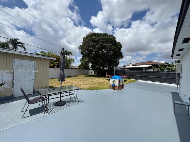 view of patio featuring an outbuilding, outdoor dining area, a fenced backyard, and a shed