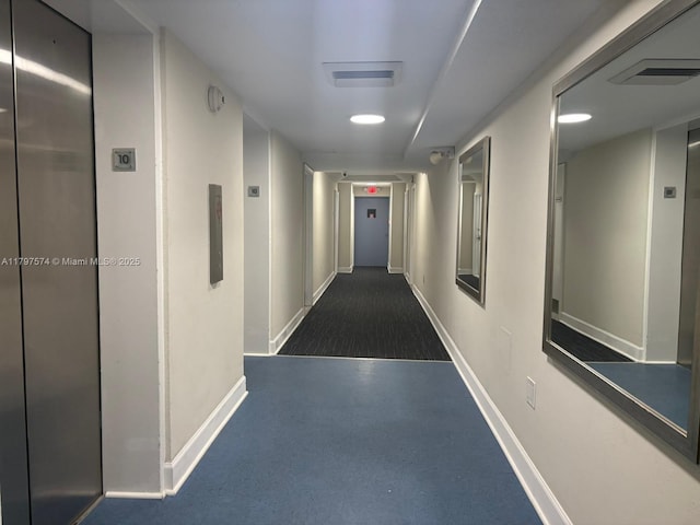 corridor with elevator, baseboards, and visible vents