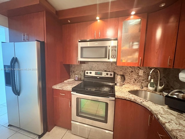 kitchen featuring a sink, light stone counters, light tile patterned floors, and appliances with stainless steel finishes
