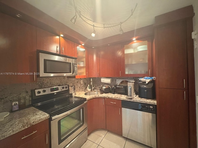 kitchen with light stone countertops, stainless steel appliances, backsplash, and a sink