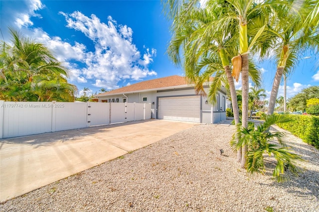 207 SW 11th St, Dania Beach, FL 33004 - view of front of home featuring fence, a garage, stucco siding, concrete driveway, and a gate