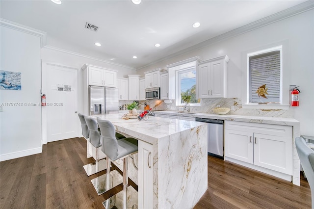 207 SW 11th St, Dania Beach, FL 33004 - kitchen with stainless steel appliances, a sink, ornamental molding, white cabinets, and light stone counters