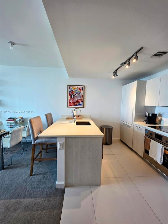 501 NE 31st St Unit 2802, Miami, FL 33137 - kitchen featuring stainless steel oven, rail lighting, light countertops, light tile patterned flooring, and modern cabinets