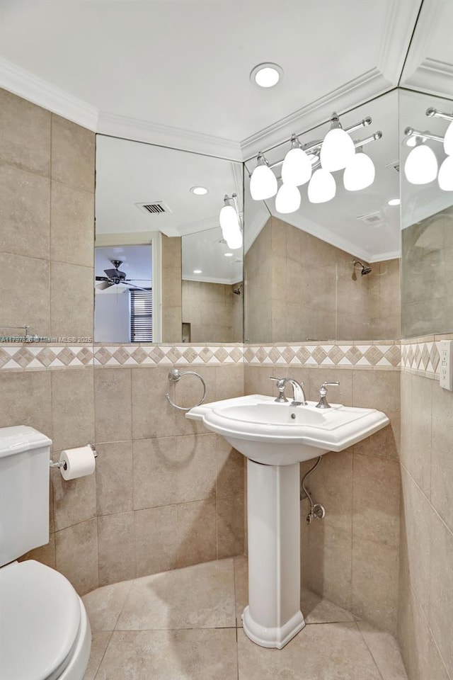 bathroom featuring tile walls, toilet, tile patterned floors, crown molding, and ceiling fan