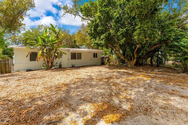 back of property featuring stucco siding and fence