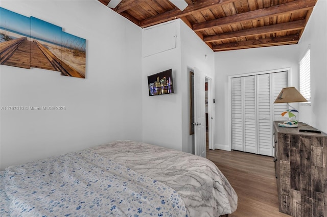 bedroom featuring wood ceiling, wood finished floors, a closet, baseboards, and beamed ceiling