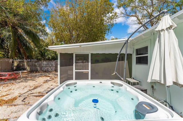 exterior space with a sunroom, a hot tub, and fence