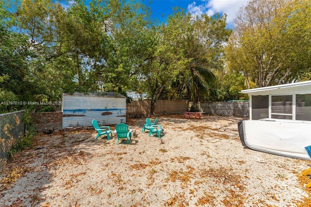 view of yard with an outbuilding, a sunroom, and a fenced backyard