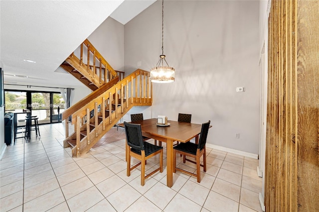 dining area featuring light tile patterned floors, a chandelier, baseboards, and stairs