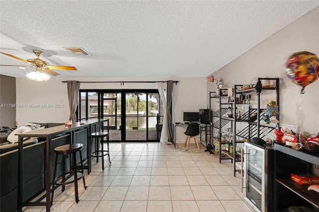 interior space featuring ceiling fan, a textured ceiling, visible vents, and beverage cooler