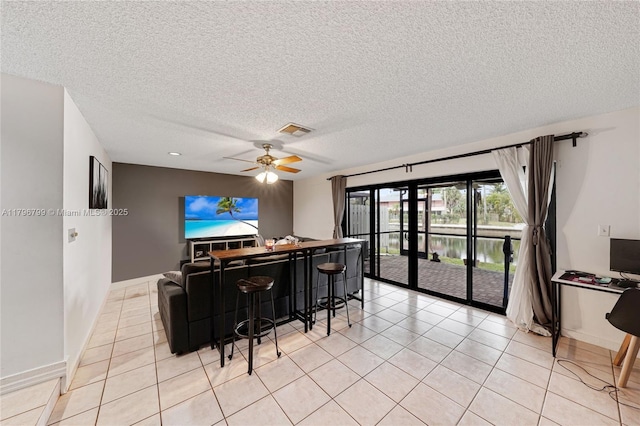 interior space featuring light tile patterned floors, visible vents, ceiling fan, and a textured ceiling