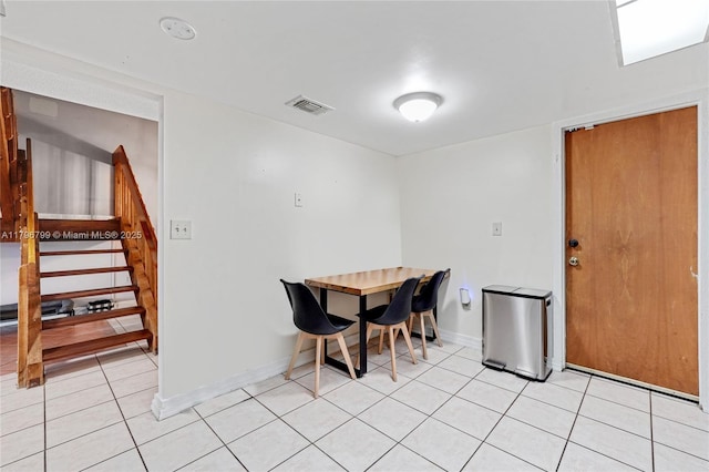 dining space with light tile patterned floors, baseboards, visible vents, and stairway