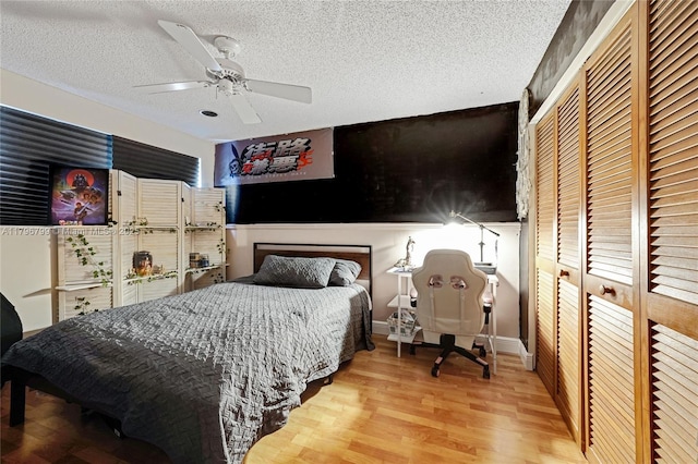 bedroom featuring a textured ceiling, a closet, a ceiling fan, and wood finished floors