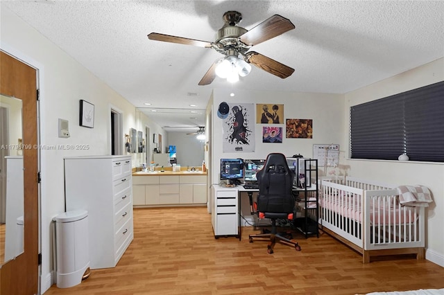 office space featuring light wood-type flooring, ceiling fan, and a textured ceiling