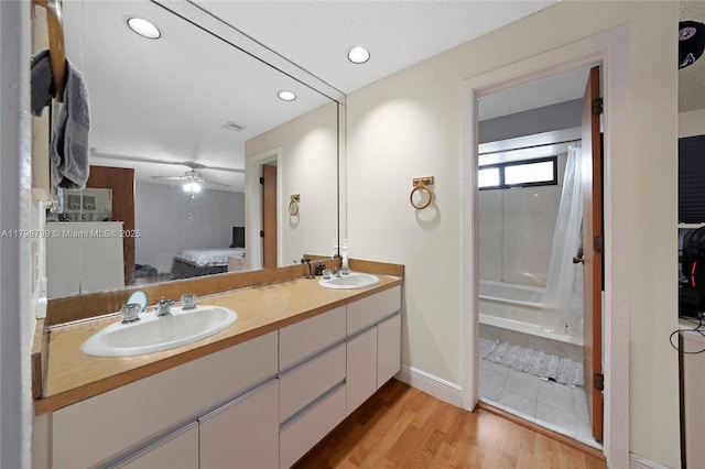 full bath with double vanity, ensuite bath, wood finished floors, and a sink