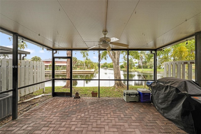 unfurnished sunroom with a ceiling fan and a water view