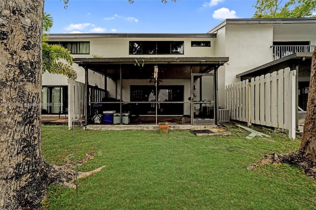 rear view of property featuring a yard, a sunroom, and stucco siding
